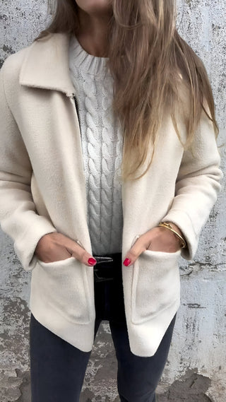 Elnara Jacke in elegantem Cremeweiß mit schlichtem Design und praktischen Fronttaschen. Die weiche Textur und bequeme Passform machen sie ideal für kühle Tage. Perfekt für einen zeitlosen, stilvollen Look.