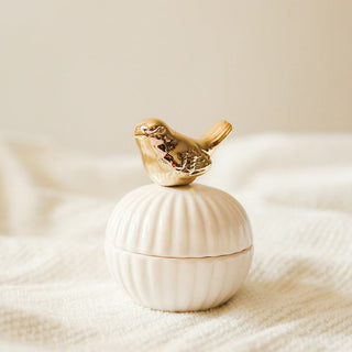 Die Hilma Schmuckdose mit einem goldenen Vogel-Design auf dem Deckel, der auf einer weißen Muschelform sitzt. Diese elegante und praktische Schmuckdose eignet sich hervorragend zur Aufbewahrung von Schmuck und kleinen Gegenständen. Der goldene Vogel verleiht der Dose einen verspielten und stilvollen Akzent. Ideal für das Zuhause, um Ordnung zu schaffen und gleichzeitig einen dekorativen Akzent zu setzen.