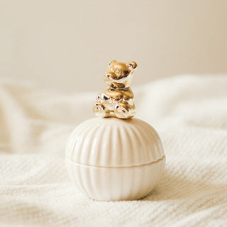 Die Hilma Schmuckdose mit einem goldenen Teddybär-Design auf dem Deckel, der auf einer weißen Muschelform sitzt. Diese charmante Schmuckdose ist nicht nur praktisch für die Aufbewahrung von Schmuck, sondern auch ein elegantes Dekorationsstück. Der goldene Teddybär verleiht ihr einen verspielten und liebevollen Akzent. Perfekt für jedes Zuhause, um Ordnung zu schaffen und dabei einen stilvollen Touch zu bieten.