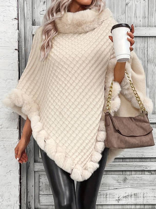 Eine Frau trägt einen cremefarbenen Kapuzenpullover mit weichem, flauschigem Kragen und Randverzierung. Der Pullover hat ein schönes Strickmuster und ist an den Kanten mit flauschigem Material verziert, was ihm ein luxuriöses und elegantes Aussehen verleiht. Sie hält eine Kaffeetasse in der Hand und trägt eine modische Handtasche mit Kettenriemen. Der Look wird mit schwarzen Leggings kombiniert, was dem Outfit eine sportliche, aber dennoch stilvolle Note verleiht.