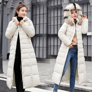 Das Bild zeigt zwei Frauen, die jeweils einen langen, weißen Wintermantel tragen, der mit einem praktischen Reißverschluss versehen ist. Beide Mäntel sind leicht gepolstert und haben einen flauschigen Pelzkragen, der für zusätzlichen Komfort und Wärme sorgt. Die Frauen tragen den Mantel in einem winterlichen Stadtbild, eine hat den Kragen hochgeklappt, die andere trägt ihn offen. Ihre Outfits sind perfekt für kaltes Wetter und kombinieren Funktionalität mit stilvollem Design. 