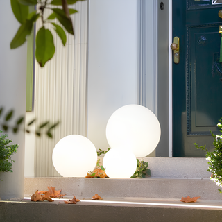 Drei leuchtende Urbana Gartenlichter in Kugelform auf einer eleganten Eingangstreppe. Energieeffizient und stilvoll, perfekt für die Beleuchtung von Eingangsbereichen, Gärten oder Terrassen. Ergänzt durch herbstliche Blätter und Grünpflanzen für eine einladende Atmosphäre.