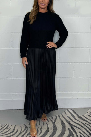 Urbana Plissierter Rock in elegantem Schwarz, kombiniert mit einem schwarzen, schlichten Strickpullover. Der klassische Look zeichnet sich durch den fließenden Faltenwurf und die zeitlose Eleganz aus – perfekt für besondere Anlässe und stilvolle Alltagsmomente.