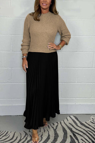 Urbana Plissierter Rock in elegantem Schwarz, kombiniert mit einem beigen Strickpullover. Der lange, fließende Plisseerock verleiht dem Outfit einen klassischen und stilvollen Look – ideal für besondere Anlässe oder den Alltag.