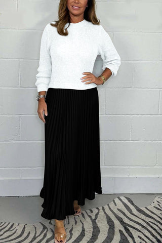 Urbana Plissierter Rock in klassischem Schwarz, kombiniert mit einem eleganten weißen Pullover. Das fließende Design des Rocks sorgt für einen stilvollen und femininen Look – ideal für formelle oder lässige Anlässe.